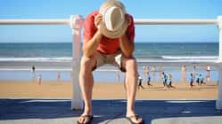 Symbolbild: Mann sitzt frustriert am Strand