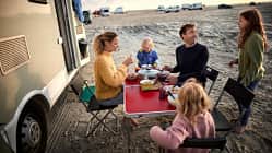 Family having dinner at table at camper van