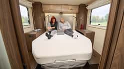 EuraMobil Integra LineGT 726 QF, Wohnmobil, Innenraum, Doppelbett, Campingfahrzeug, Reisemobil, Schlafbereich, Wohnmobil-Innenausstattung, Reise, Komfort Innenraumaufnahme eines EuraMobil Integra LineGT 726 QF Wohnmobils mit zwei Personen auf dem Bett.