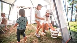 Eco-Friendly Travels: Mom in the Tent Kitchen Caring for Clean Dishes.