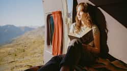 Woman reading book in camper van in mountains Woman reading book in camper van in mountains