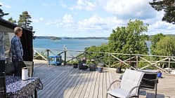Schweden, Terrasse, Seeblick, Gartenmöbel, Blumentöpfe, Landschaft, Sommer, Holzdeck, Mann, Skandinavien Terrasse mit Blick auf einen See in Schweden, ein Mann steht am Rand, Gartenmöbel und Blumentöpfe sichtbar.
