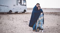 Kühler Morgen am Strand, Pärchen in Decken gewickelt, Wohnmobil