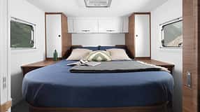 Heckschlafzimmer im Corigon T 75 LQ Pure (2027) mit Queensbett, Kleiderschränken, Fenstern links und rechts sowie Dachfenster.