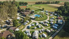 Drohnenaufnahme des Campingplatzes der Terme Banovci mit Stellplätzen, Pool und herbstlicher Landschaft.