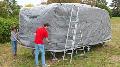 Die Schutzhülle wird von vorne nach hinten über den Caravan gezogen.