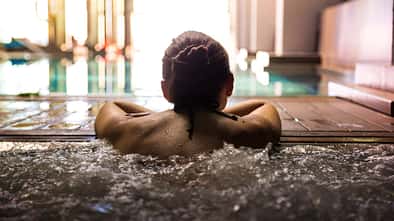 Woman relaxing in a hot tub pool during weekend days of relax and spa in a luxury place during travel vacations.