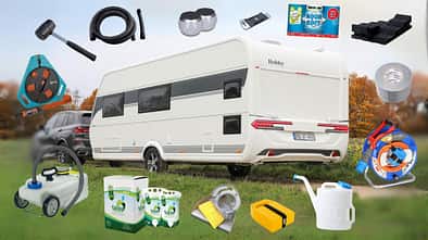 Ein Caravan wird von einem Auto gezogen. Drumherum ist Zubehör fürs Camping platziert.
