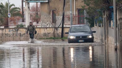 A man and a car try to cross a flooded road in Schiavonea, a