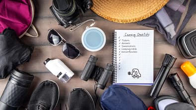 Symbolbild Packliste Festivalcamping: Campingzubehör und Notizzettel