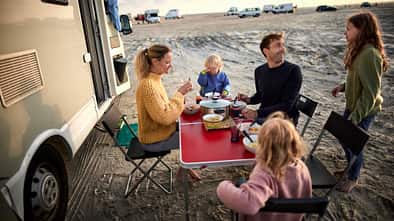 Family having dinner at table at camper van