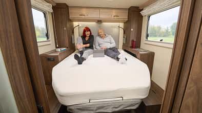 Innenraumaufnahme eines EuraMobil Integra LineGT 726 QF Wohnmobils mit zwei Personen auf dem Bett.