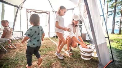 Eco-Friendly Travels: Mom in the Tent Kitchen Caring for Clean Dishes.