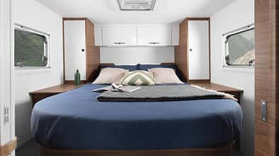 Heckschlafzimmer im Corigon T 75 LQ Pure (2027) mit Queensbett, Kleiderschränken, Fenstern links und rechts sowie Dachfenster.