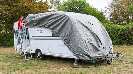 Die Schutzhülle wird von vorne nach hinten über den Caravan gezogen.