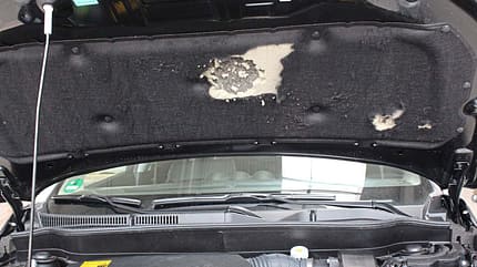 Zerkratzte Dämmmatte an der Motorhaube.