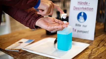 Close-up of man cleaning hands with hand sanitizer at pharmacy