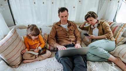Father, mother and little daughter with gadgets sitting in the camper Father, mother and little daughter with gadgets sitting in the camper