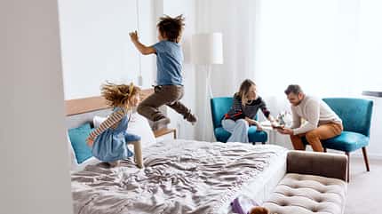 Brother and sister playing and jumping on the bed in the hotel room Brother and sister playing and jumping on the bed in the hotel room