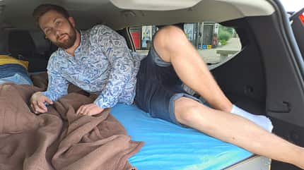 Dacia, Jogger, Microcamper, Car-Camping, Übernachten Junger Mann liegt im Heck des Dacia Jogger.