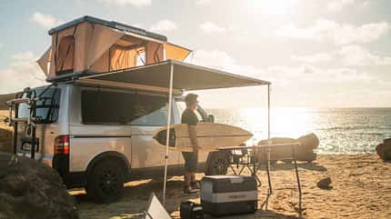 Surf, Sonne, Salz: Prime Tech Utah Dachzelt am Strand, Markise ausgefahren, das Meer im Rücken. Perfektes Setup für alle, die Wellen lieben und unter freiem Himmel träumen.