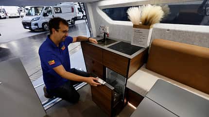 Innenküche im Lidu Aquila 360 mit anthrazitfarbener Arbeitsfläche, Induktionskochfeld, Spüle und kleinem Kühlschrank.
