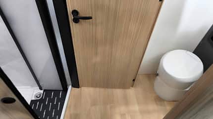 Raumbad, Innenraum, Sanitär, Tür Raumbad mit Dusche, Waschbecken und WC im Mooveo INT-78 QBF Al-Ko. Moderne Fliesenoptik und helle Beleuchtung schaffen ein angenehmes Ambiente.