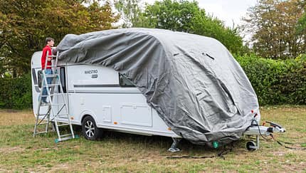 Die Schutzhülle wird von vorne nach hinten über den Caravan gezogen.