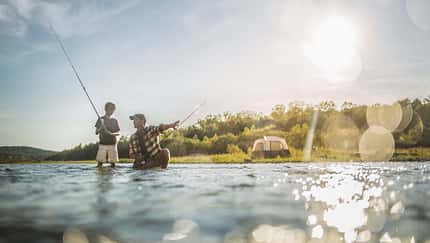 Caucasian father and son fishing in river