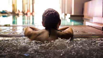Woman relaxing in a hot tub pool during weekend days of relax and spa in a luxury place during travel vacations.
