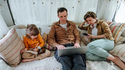 Father, mother and little daughter with gadgets sitting in the camper Father, mother and little daughter with gadgets sitting in the camper