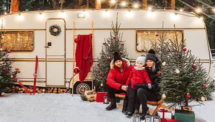 Happy family have a good time together near decorated motorhome in winter.