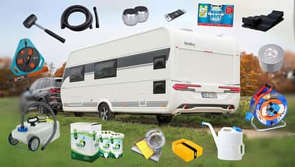 Ein Caravan wird von einem Auto gezogen. Drumherum ist Zubehör fürs Camping platziert.