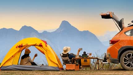 Campingszene mit orangener Zeltmontur und Carcamper