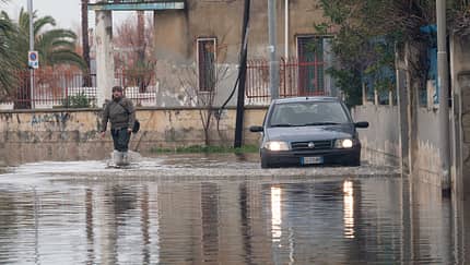 A man and a car try to cross a flooded road in Schiavonea, a