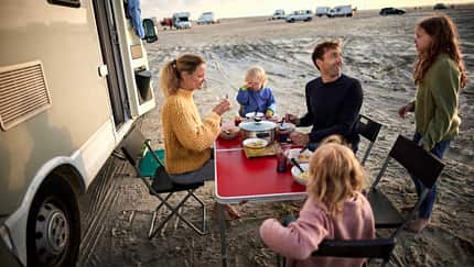 Family having dinner at table at camper van