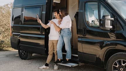 adult couple making a video call with their iPad in a camper van