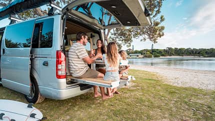 Young Family Enjoying Outdoor Meal by Scenic Sea