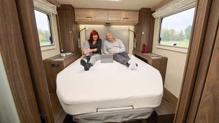 EuraMobil Integra LineGT 726 QF, Wohnmobil, Innenraum, Doppelbett, Campingfahrzeug, Reisemobil, Schlafbereich, Wohnmobil-Innenausstattung, Reise, Komfort Innenraumaufnahme eines EuraMobil Integra LineGT 726 QF Wohnmobils mit zwei Personen auf dem Bett.