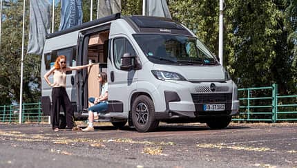 Außenaufnahme, zwei Frauen, Campingbus, offene Aufbautür Zwei Frauen vor Hobby ONTOUR VAN 600 FT – Campingbus mit geöffneter Aufbautür, Vanlife-Alltag und Reisevorbereitung.