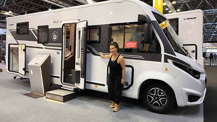 Benimar Amphitryon A968 (2027), Außenansicht, Beifahrerseite, Frau, Messe, Caravan Salon 2026 Außenansicht des Benimar Amphitryon A968 (2027) auf dem Caravan Salon 2026, Beifahrerseite mit Frau als Größenvergleich.