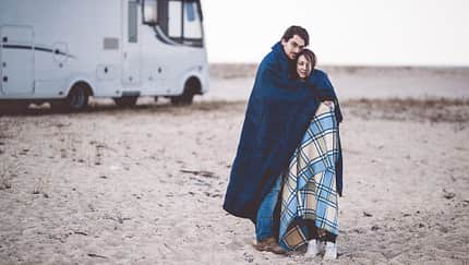 Kühler Morgen am Strand, Pärchen in Decken gewickelt, Wohnmobil
