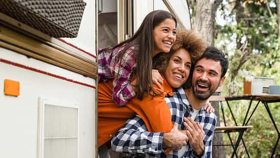 Mom dad and daughter mixed-race family driving van home on wheels camper together. Adventure on caravanning. Road trip voyage with children kids