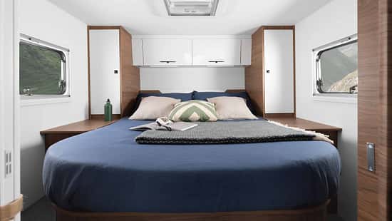 Heckschlafzimmer im Corigon T 75 LQ Pure (2027) mit Queensbett, Kleiderschränken, Fenstern links und rechts sowie Dachfenster.