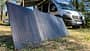 Solarpanel, Campingbus, Photovoltaik, Camping, Stromversorgung, Outdoor, Vanlife, Solarmodul, Energieversorgung, Wald Tragbares Solarpanel auf dem Boden vor einem Campingbus im Wald.