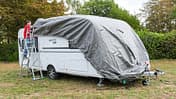 Die Schutzhülle wird von vorne nach hinten über den Caravan gezogen.