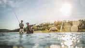 Caucasian father and son fishing in river