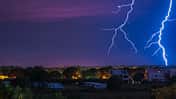 Two large and powerful lighting strikes crossing night blue sky