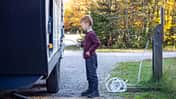 Little Boy Connecting Water Hose to Camper Trailer on Campground in Autumn, Quebec, Canada