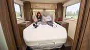 Innenraumaufnahme eines EuraMobil Integra LineGT 726 QF Wohnmobils mit zwei Personen auf dem Bett.